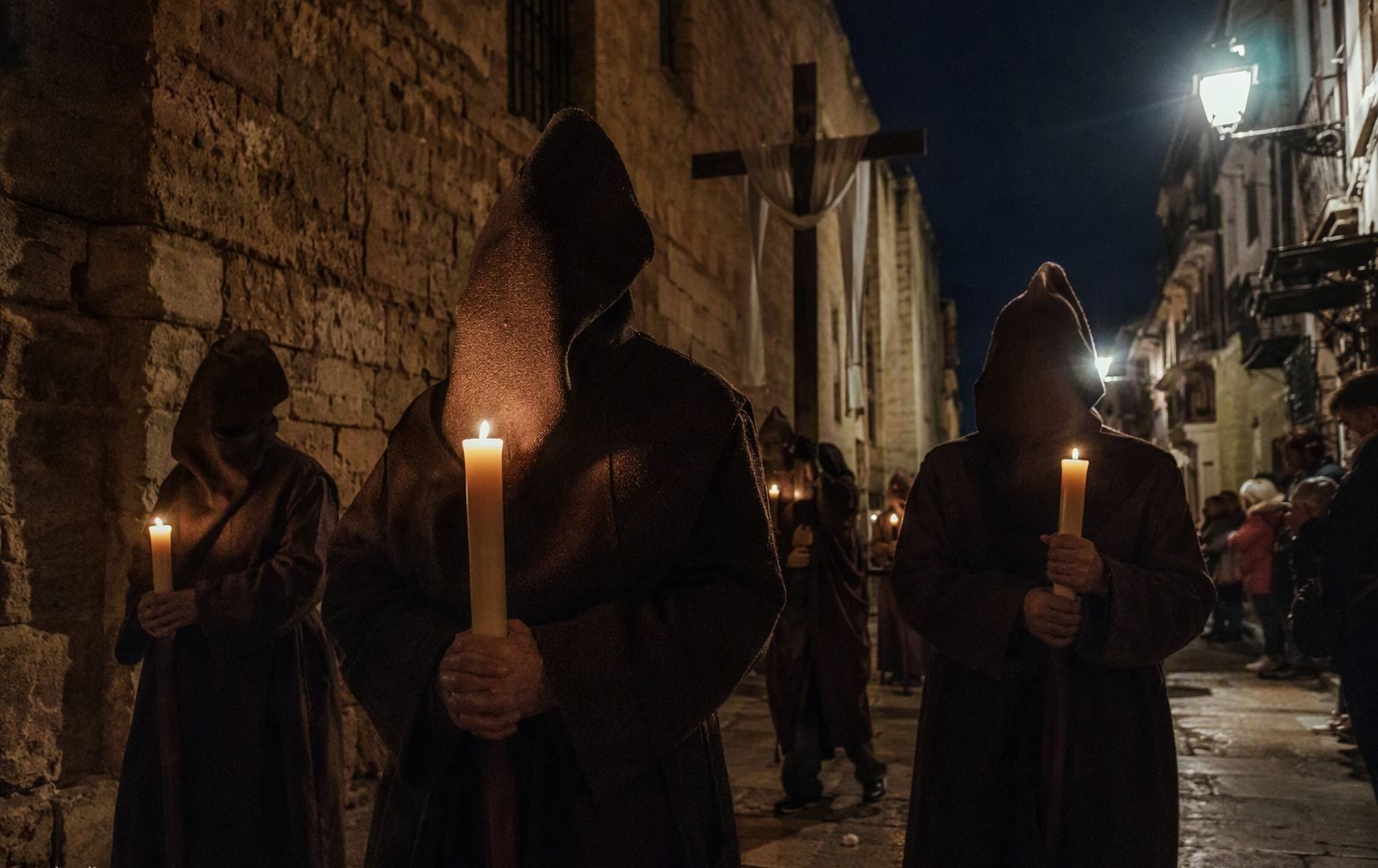 Penitents in dark Capas Pardas robes carrying candles through Zamora at night